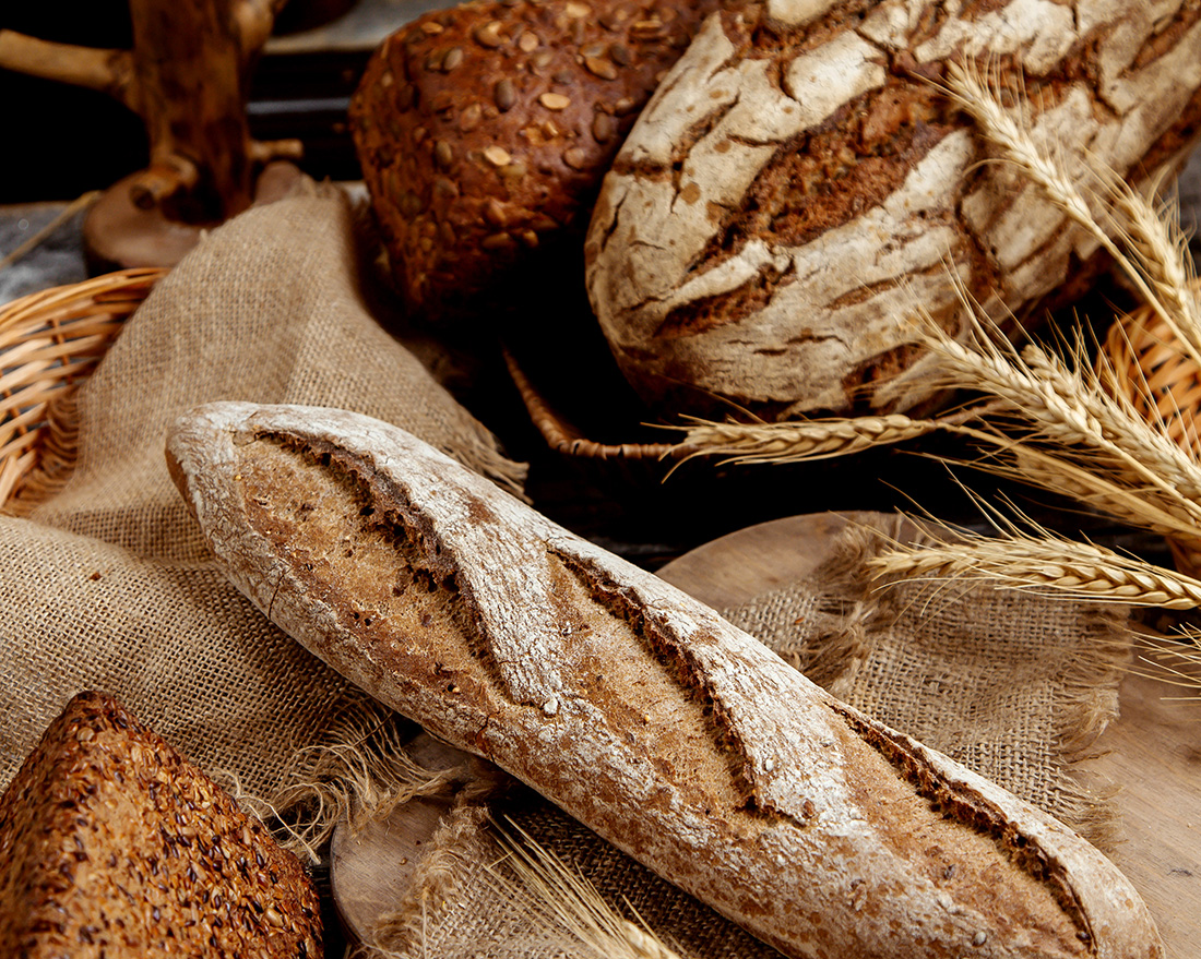 Pains rustiques - miches et baguettes sur toile de jute, gros plan