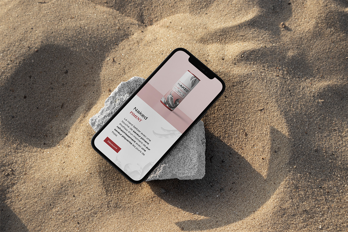 Site Naked en mobile — mockup smartphone posé sur sable